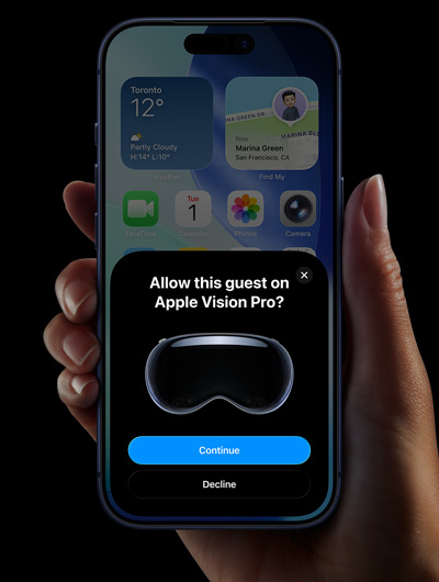 A hand holding an iPhone. The iPhone's screen displays a window with the message, "Allow this guest on Apple Vision Pro?" with buttons labelled "Continue" and "Decline."