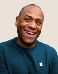 Portrait of a smiling Apple Retail team member with short, dark gray hair.