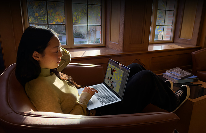 Seseorang sedang duduk di kursi sambil menggunakan MacBook Air