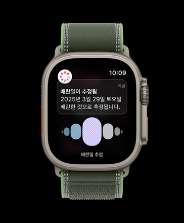 건강 앱 생리 주기 추적의 배란 추정일 알림이 표시된 내추럴 티타늄 케이스의 Apple Watch Ultra 3, 그리고 블루/브라이트 블루 트레일 루프