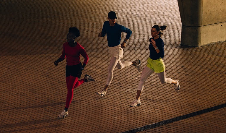 Kobieta rozciąga się na podłodze, sięgając ręką do nogi. Ma na ręku Apple Watch Series 10; na ekranie: Trening, Schładzanie, Aktywność, Pierścienie aktywności