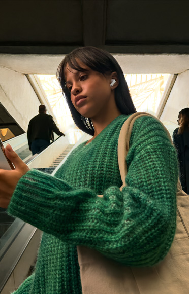 AirPods Pro 3を装着してiPhoneを見ている人物