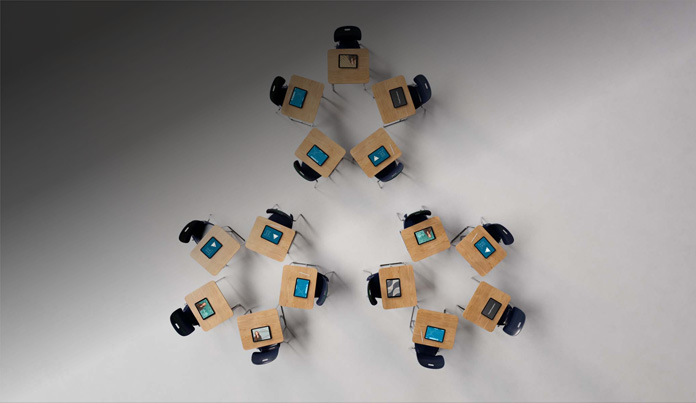 Multiple iPad devices and Apple Pencils placed on wooden desks at an elementary school