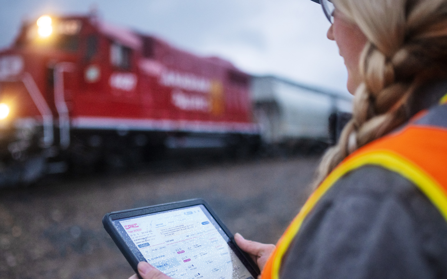 Une employée des chemins de fer vérifie les horaires des trains sur un iPad dans une gare de triage