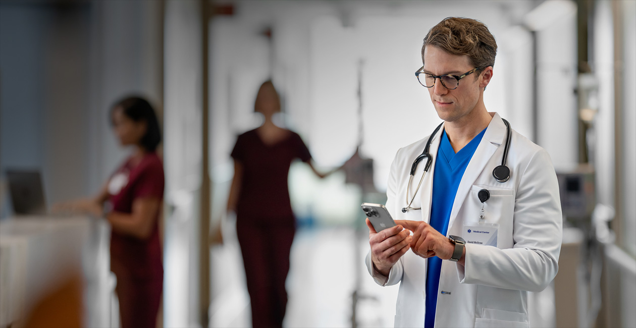 Một nam bác sĩ đang nhìn vào iPhone trong bệnh viện.