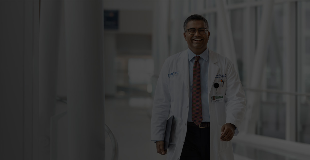 En läkare går med en MacBook under sin högra arm.