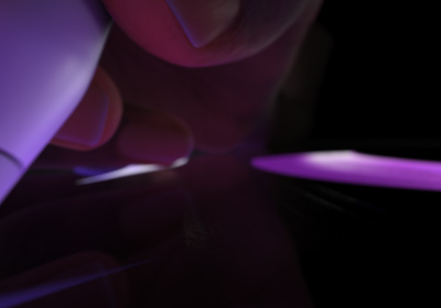 Eine Hand hält den Apple Pencil Pro in Schreibposition. Die Spitze drückt auf ein Display und es werden fette Striche in einem leuchtenden Violett gezeichnet.