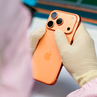 An employee in full-coverage work suit inspects an iPhone at a work station